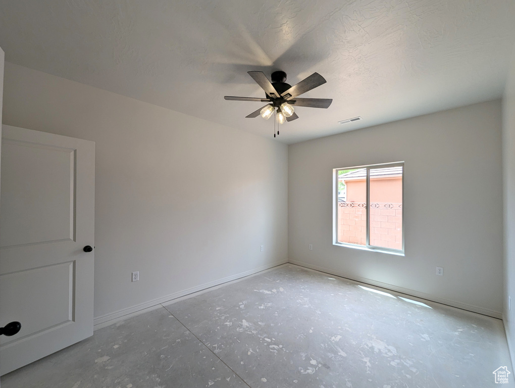 Spare room featuring ceiling fan and concrete flooring