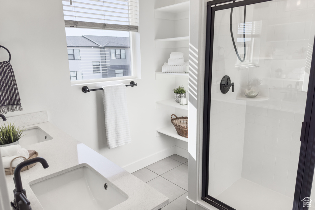 Bathroom featuring tiled shower, dual vanity, and tile floors