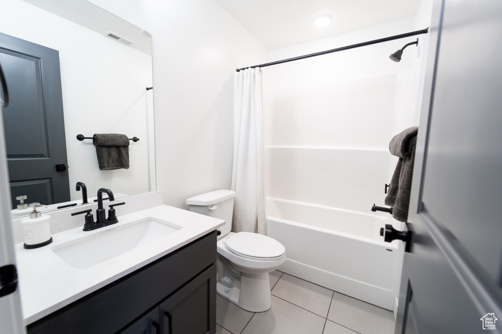 Full bathroom with tile floors, oversized vanity, shower / tub combo, and toilet