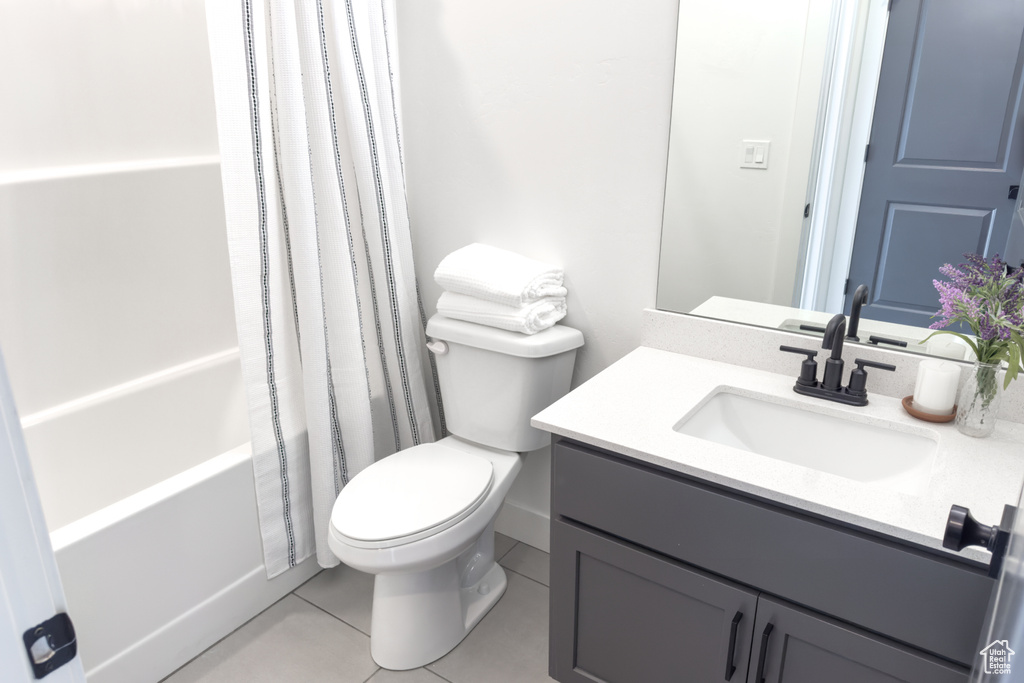 Full bathroom featuring toilet, shower / bath combo, tile floors, and vanity