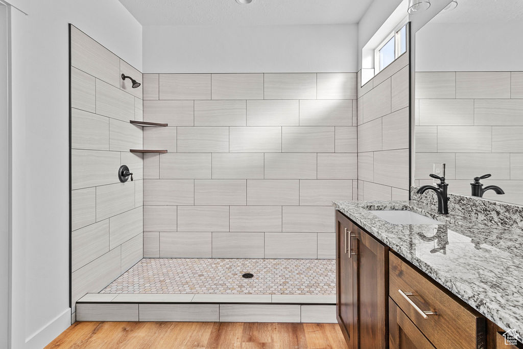 Bathroom featuring hardwood / wood-style floors, a tile shower, and vanity