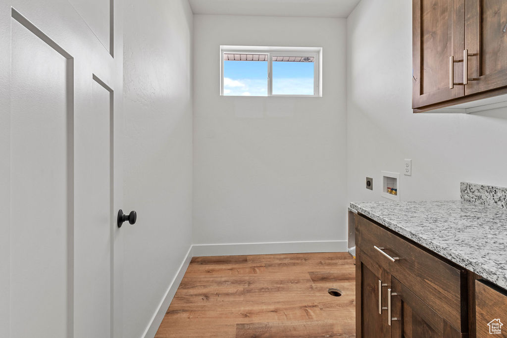 Laundry area featuring light hardwood / wood-style flooring, cabinets, and washer hookup