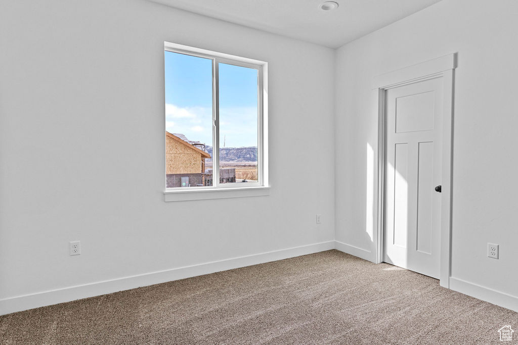 Unfurnished room with light colored carpet and plenty of natural light