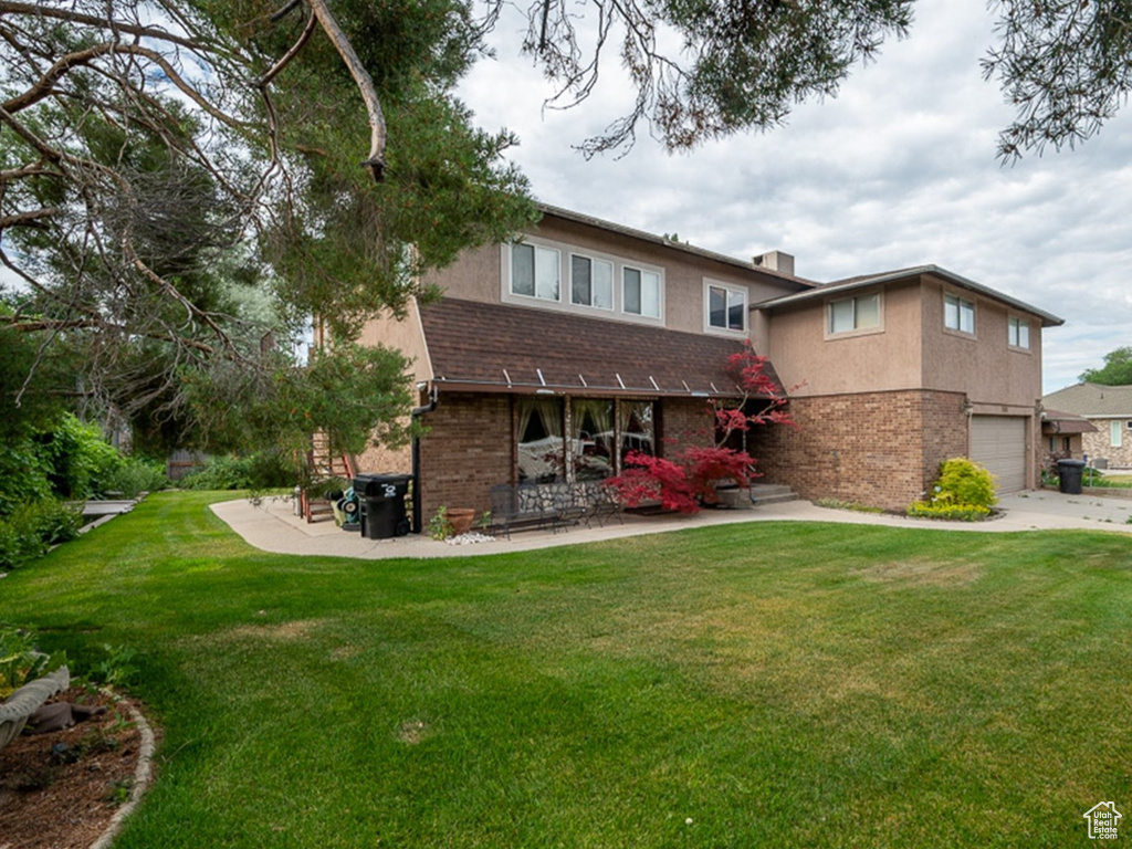 Rear view of house with a garage and a lawn