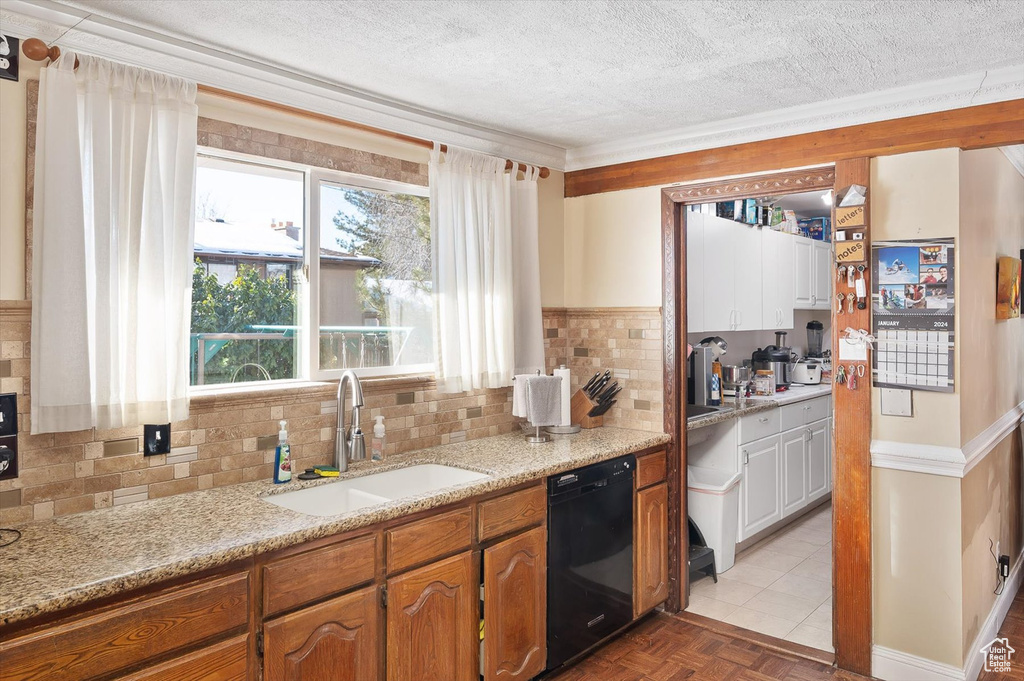 Kitchen featuring light parquet floors, black dishwasher, a textured ceiling, backsplash, and sink