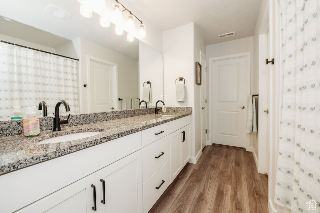 Bathroom with wood-type flooring and dual bowl vanity