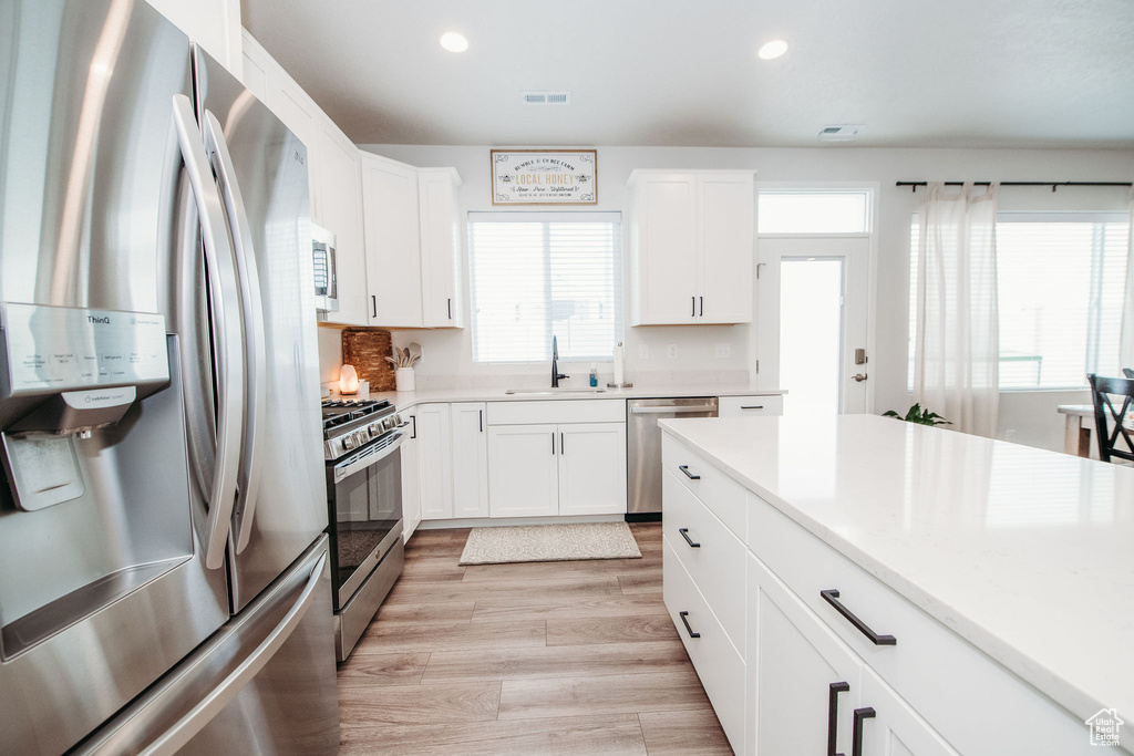 Kitchen featuring sink, white cabinets, a wealth of natural light, and stainless steel appliances