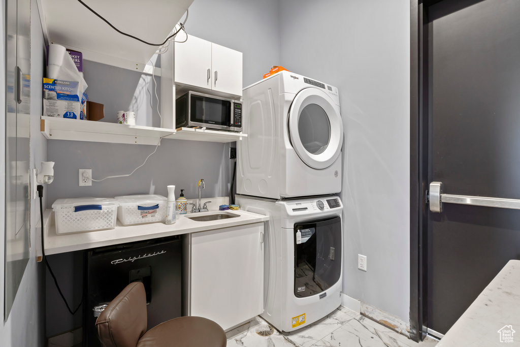 Laundry room featuring light tile floors, sink, and stacked washer / drying machine