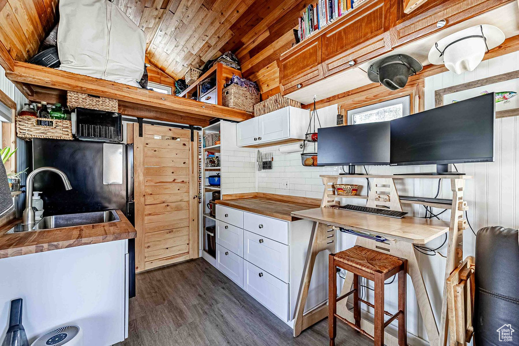 Kitchen featuring lofted ceiling, white cabinetry, dark wood-type flooring, butcher block countertops, and sink