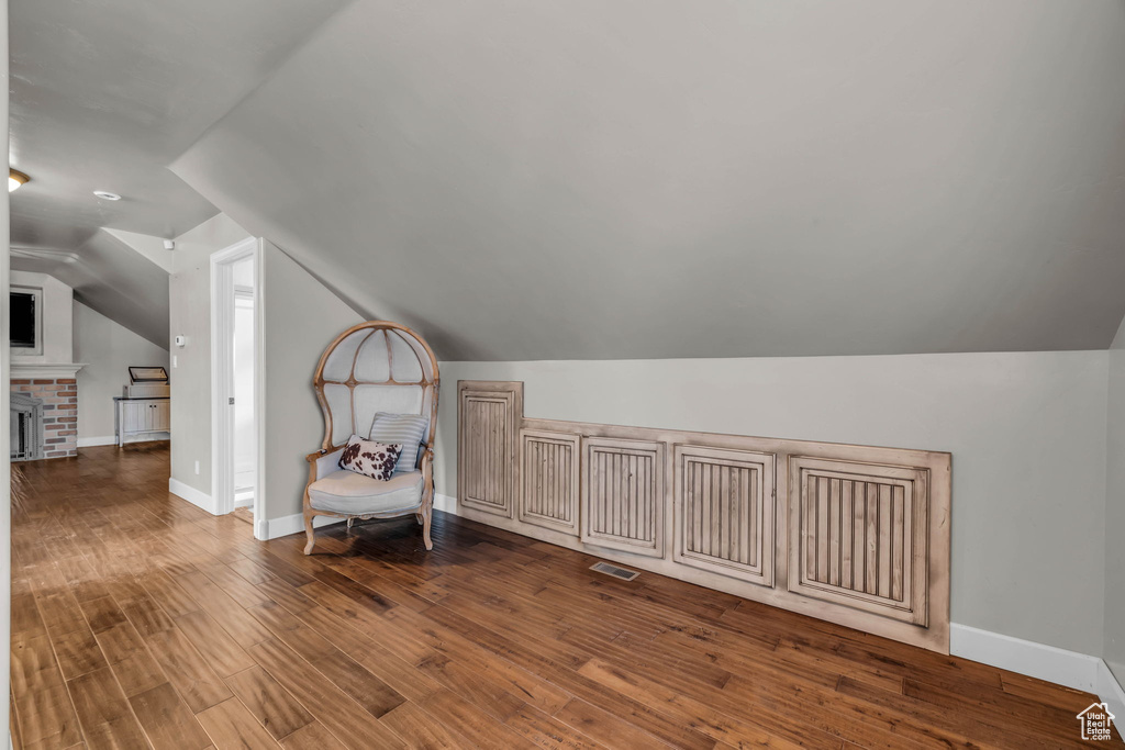 Bonus room with a fireplace, dark hardwood / wood-style floors, and lofted ceiling