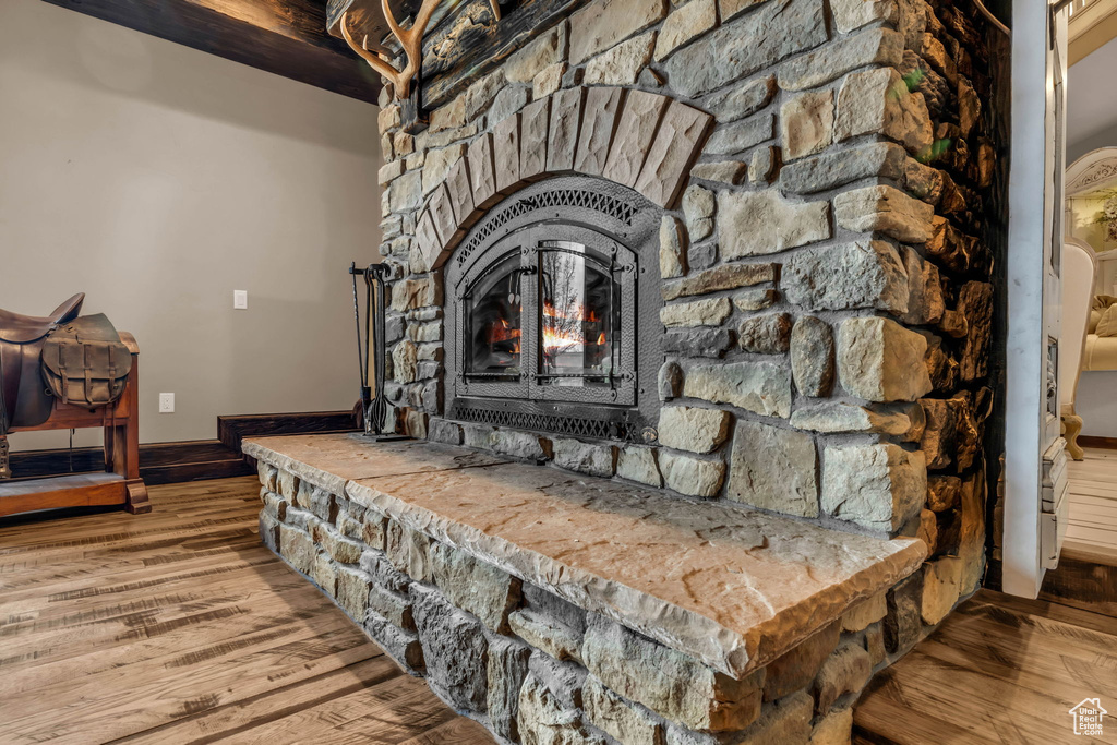 Details with beam ceiling, hardwood / wood-style floors, and a stone fireplace