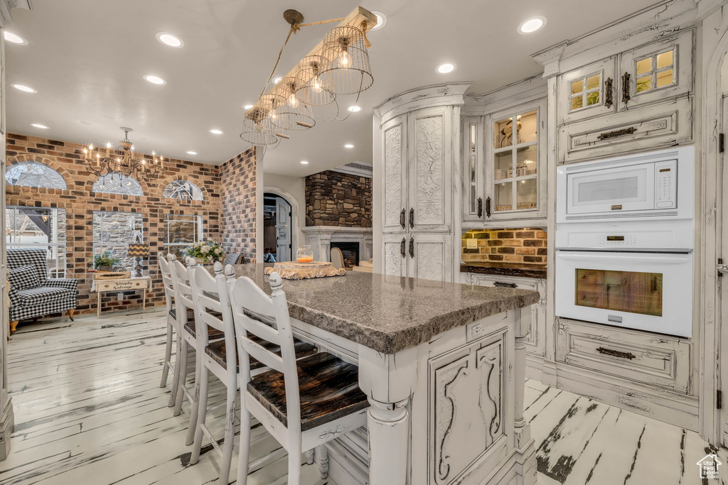 Kitchen featuring a kitchen island, light hardwood / wood-style floors, white appliances, and decorative light fixtures