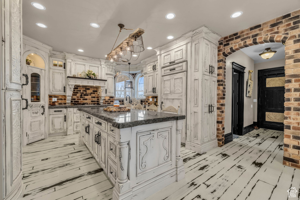 Kitchen with pendant lighting, an inviting chandelier, white cabinets, and a center island