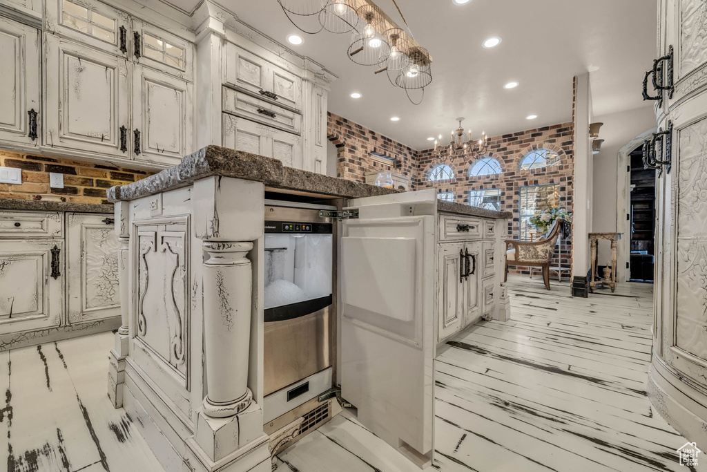 Kitchen with decorative light fixtures, dark stone countertops, light hardwood / wood-style flooring, a notable chandelier, and white cabinetry