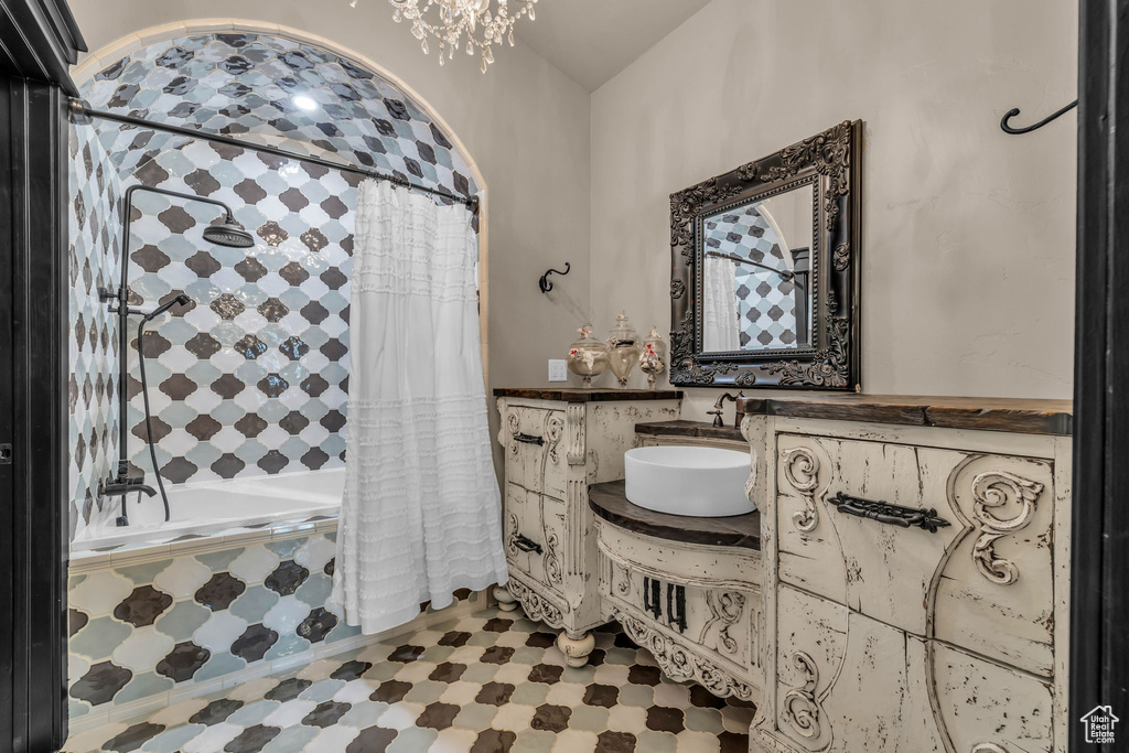 Bathroom with vanity with extensive cabinet space, shower / bath combo with shower curtain, and tile flooring