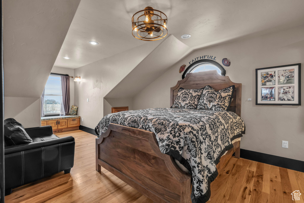 Bedroom with a chandelier, lofted ceiling, and light hardwood / wood-style floors
