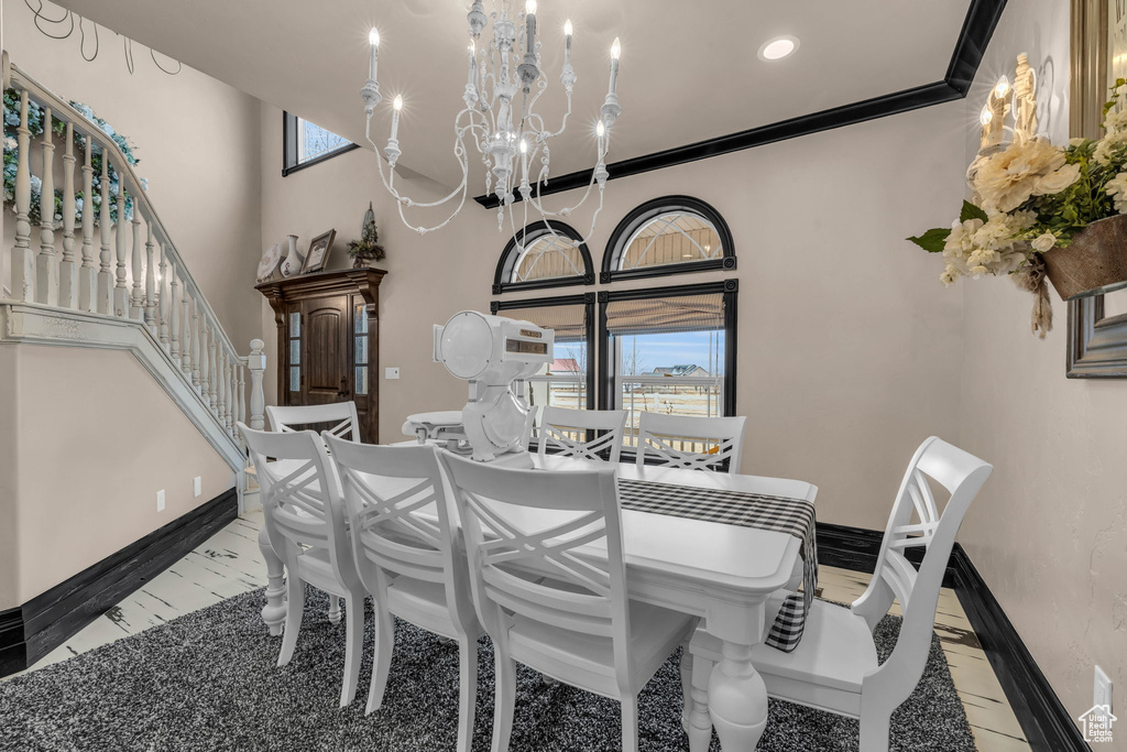 Dining space featuring a chandelier, light tile floors, crown molding, and plenty of natural light