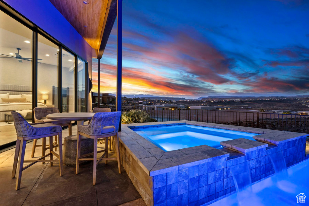 Pool at dusk with an in ground hot tub and a patio