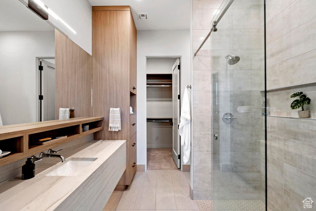 Bathroom featuring walk in shower, vanity with extensive cabinet space, and tile flooring