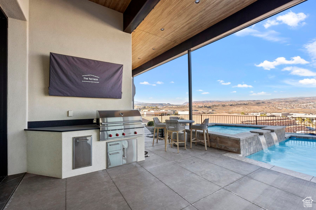 View of patio with pool water feature, exterior kitchen, a grill, and a pool with hot tub