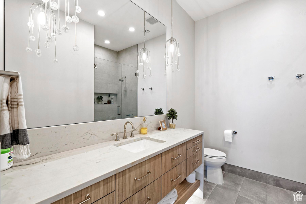 Bathroom with tile floors, toilet, vanity with extensive cabinet space, and tiled shower