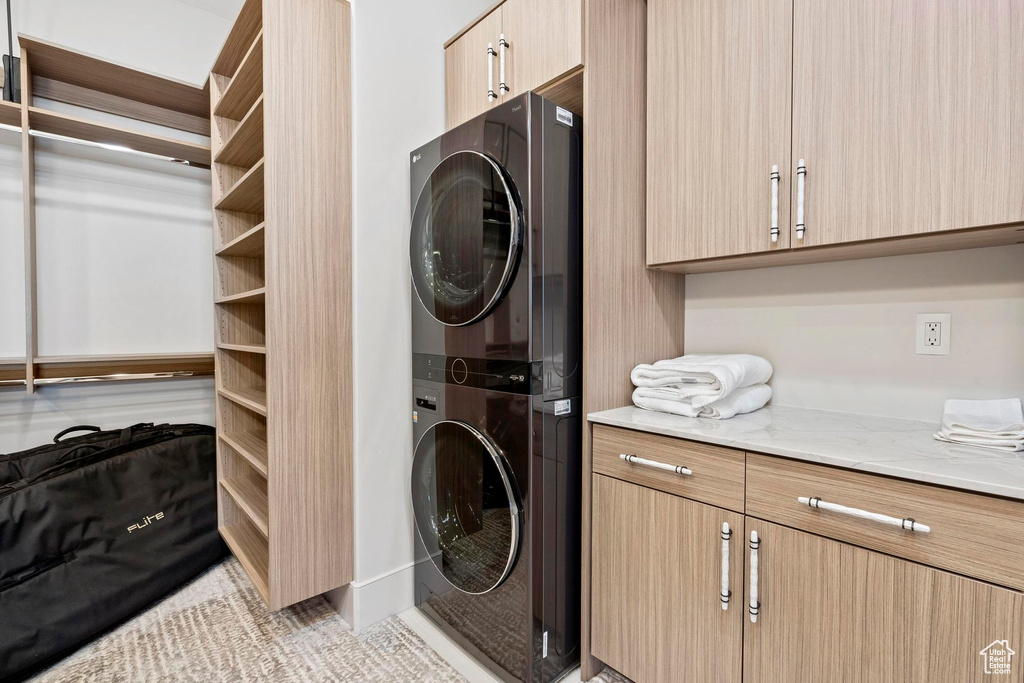 Washroom with stacked washer and dryer and cabinets