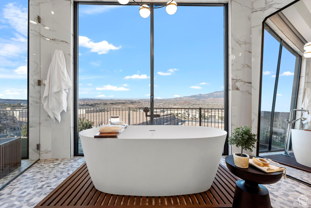 Bathroom featuring tile floors, an inviting chandelier, a bathing tub, and a mountain view