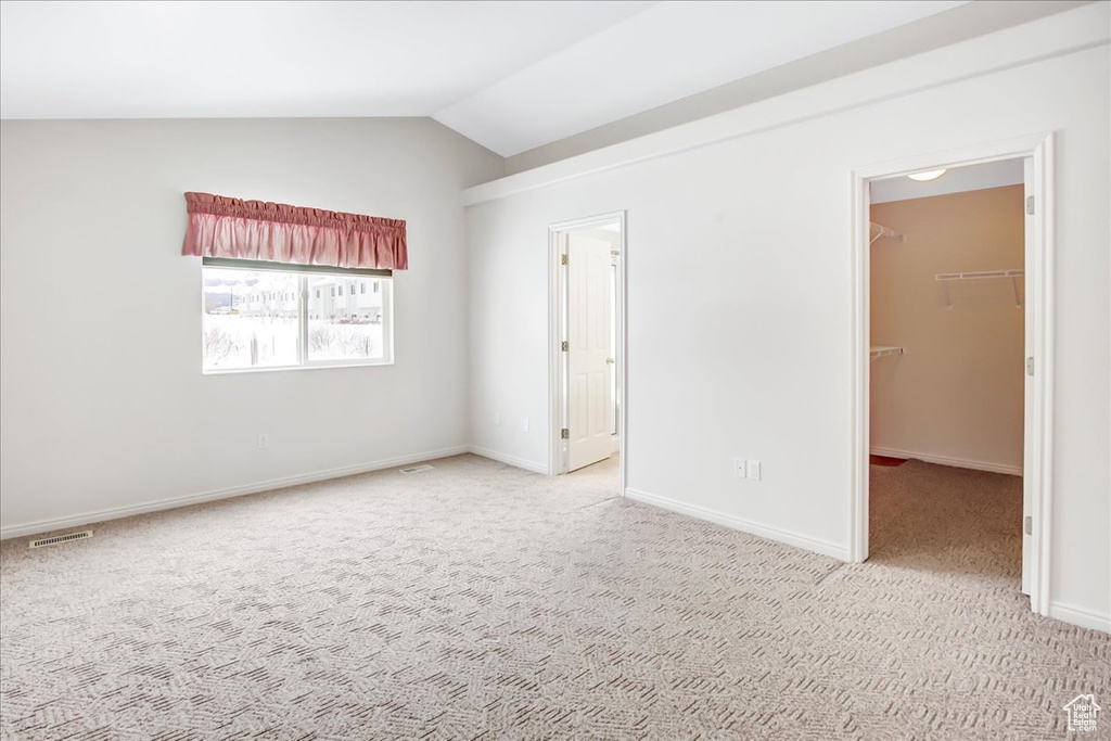 Empty room featuring vaulted ceiling and light carpet