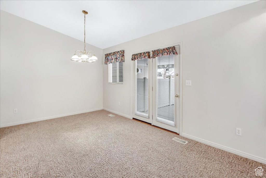 Spare room with a notable chandelier and light carpet