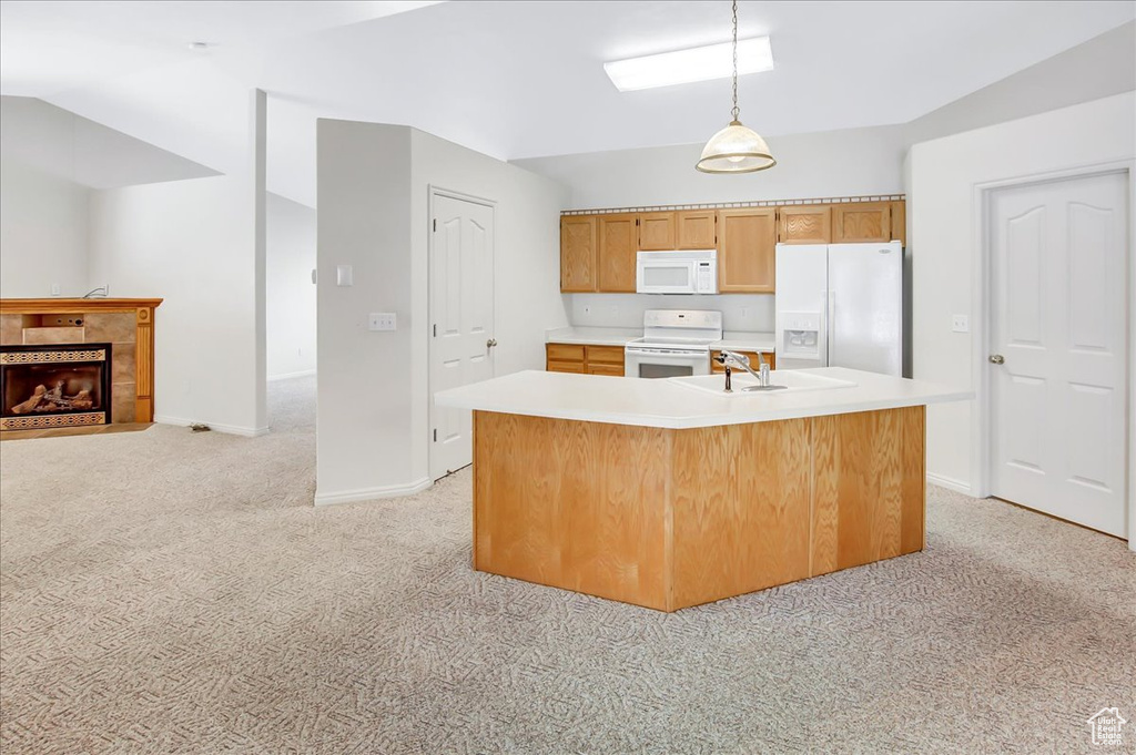 Kitchen featuring pendant lighting, white appliances, light carpet, a center island with sink, and sink