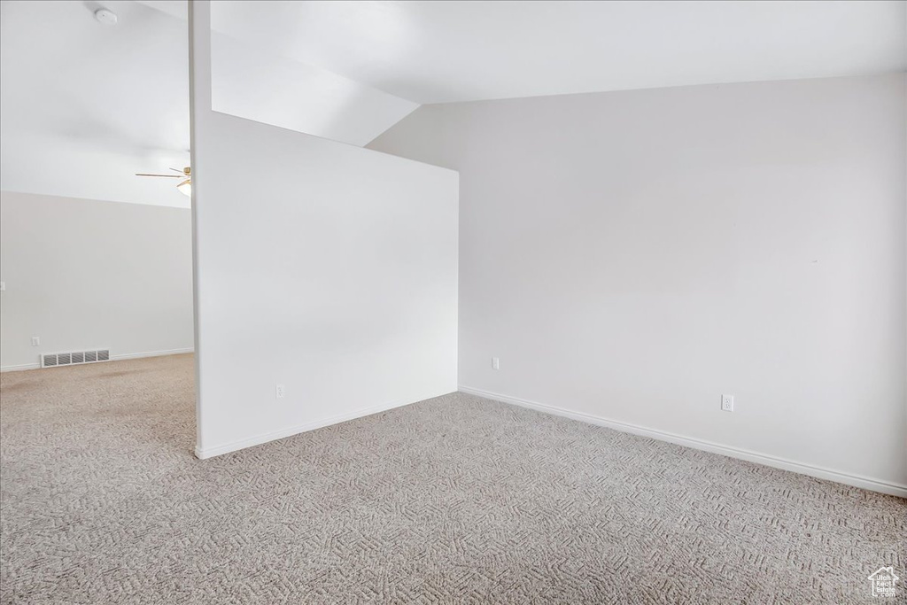Spare room featuring light colored carpet, ceiling fan, and lofted ceiling