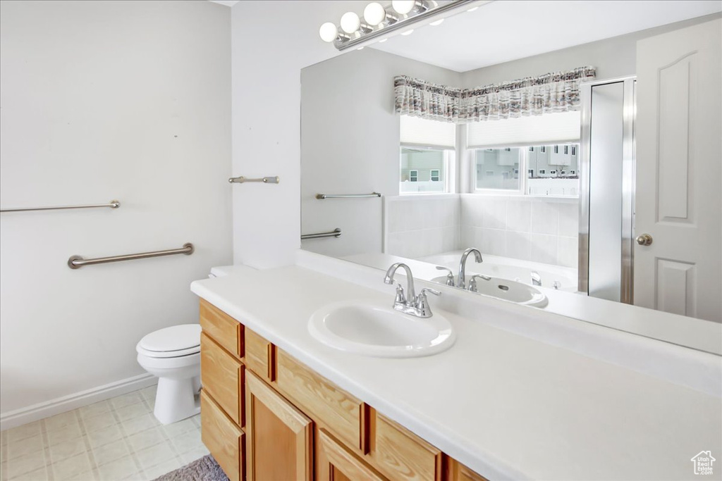 Bathroom featuring a bath to relax in, toilet, vanity with extensive cabinet space, and tile flooring