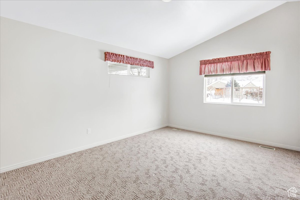 Empty room with lofted ceiling and carpet