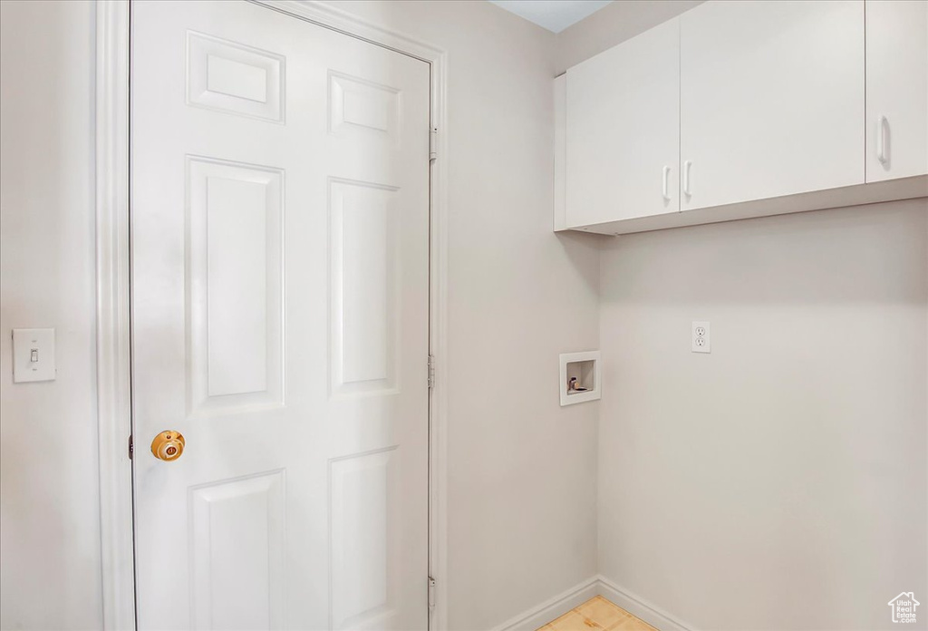 Washroom with light tile flooring, hookup for a washing machine, and cabinets