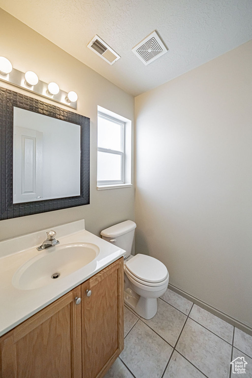 Bathroom with a textured ceiling, toilet, large vanity, and tile flooring