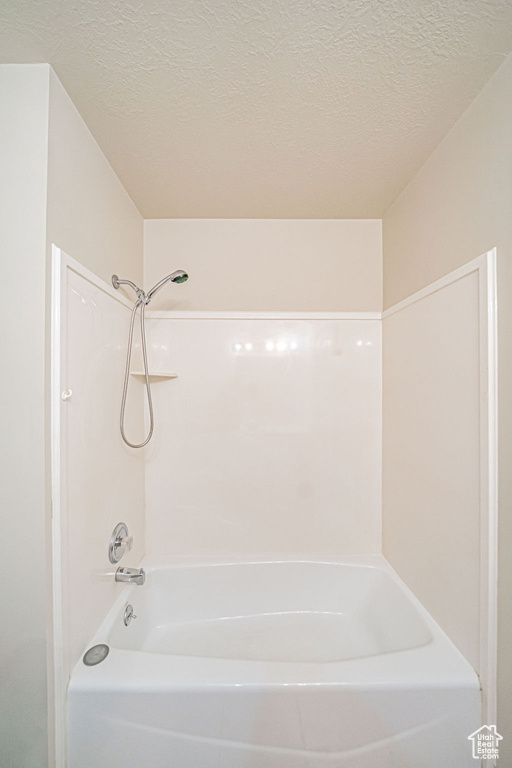 Bathroom with shower / bathing tub combination and a textured ceiling
