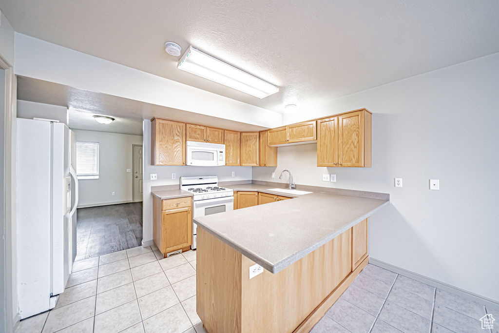 Kitchen with sink, light tile flooring, kitchen peninsula, and white appliances