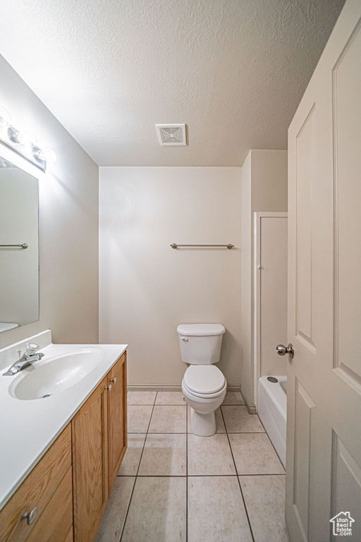 Full bathroom featuring toilet, large vanity, tile flooring, shower / bathtub combination, and a textured ceiling