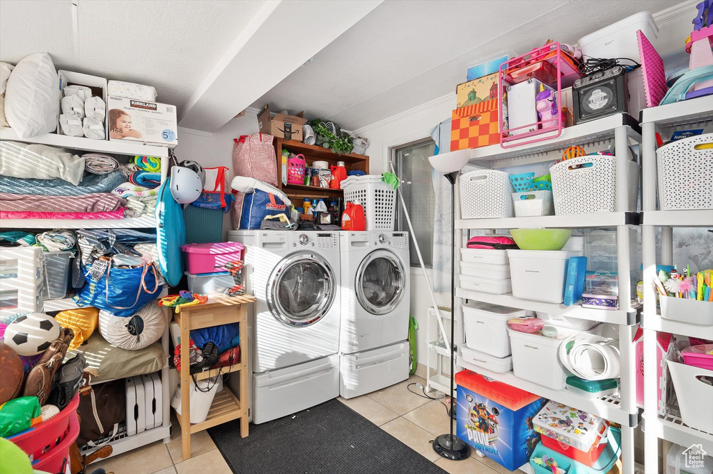 Clothes washing area with light tile floors and washing machine and dryer