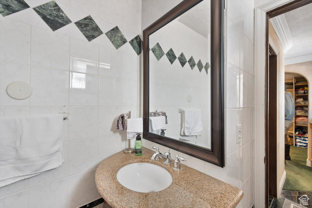 Bathroom with sink, tile walls, and a textured ceiling