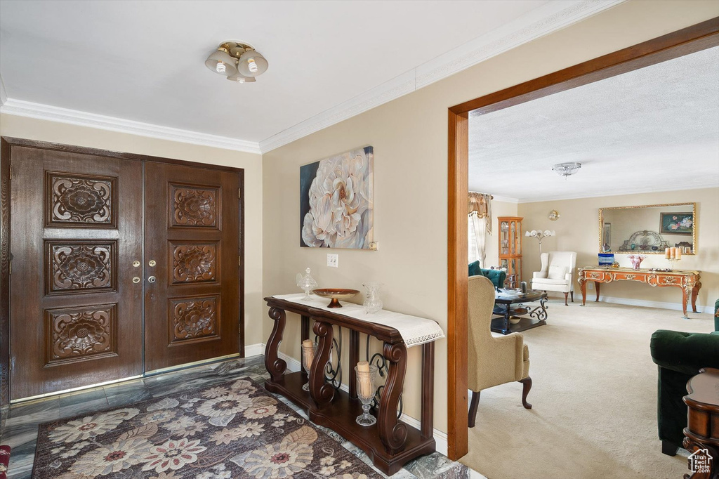 Carpeted entryway featuring crown molding