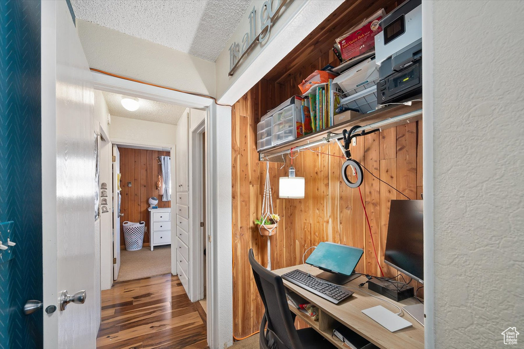 Office area featuring wood walls, a textured ceiling, and hardwood / wood-style flooring