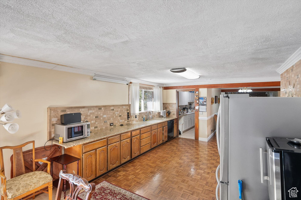 Kitchen featuring a textured ceiling, light parquet flooring, white refrigerator, and backsplash