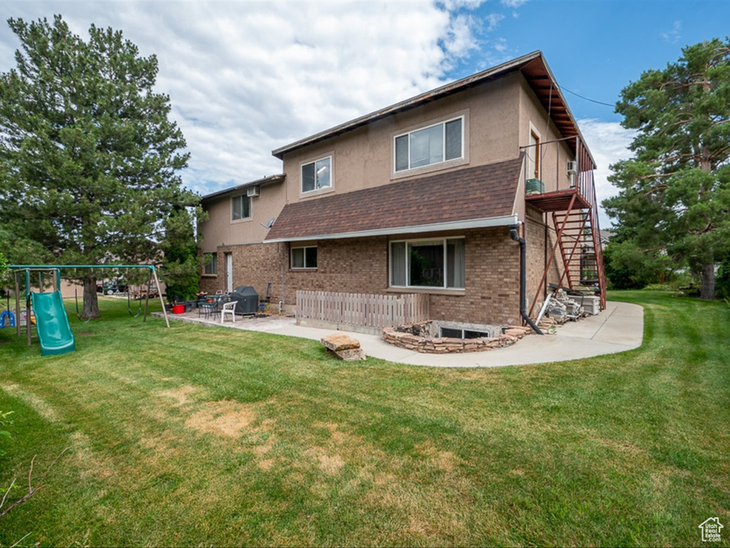 Back of house with a patio area, a playground, and a yard