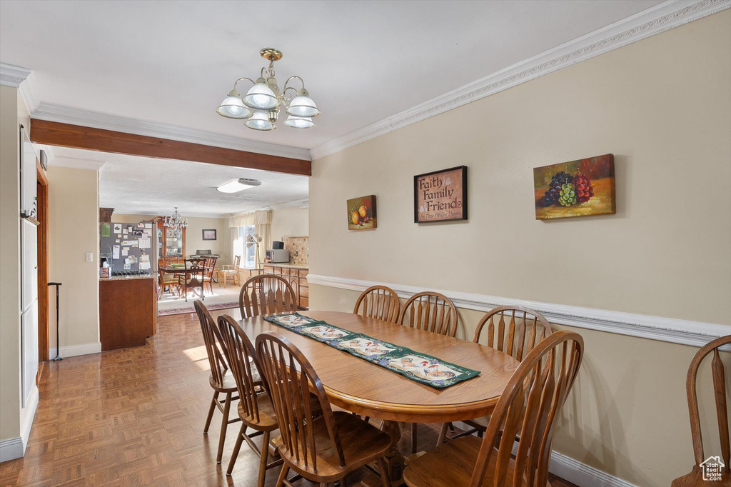 Dining area with crown molding, a chandelier, and parquet floors