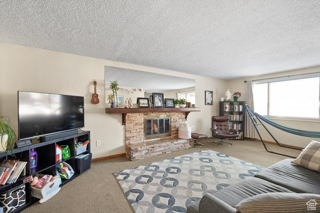 Living room featuring light colored carpet, a fireplace, and a textured ceiling