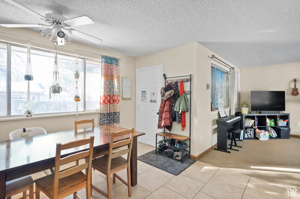 Tiled dining room featuring a textured ceiling and ceiling fan