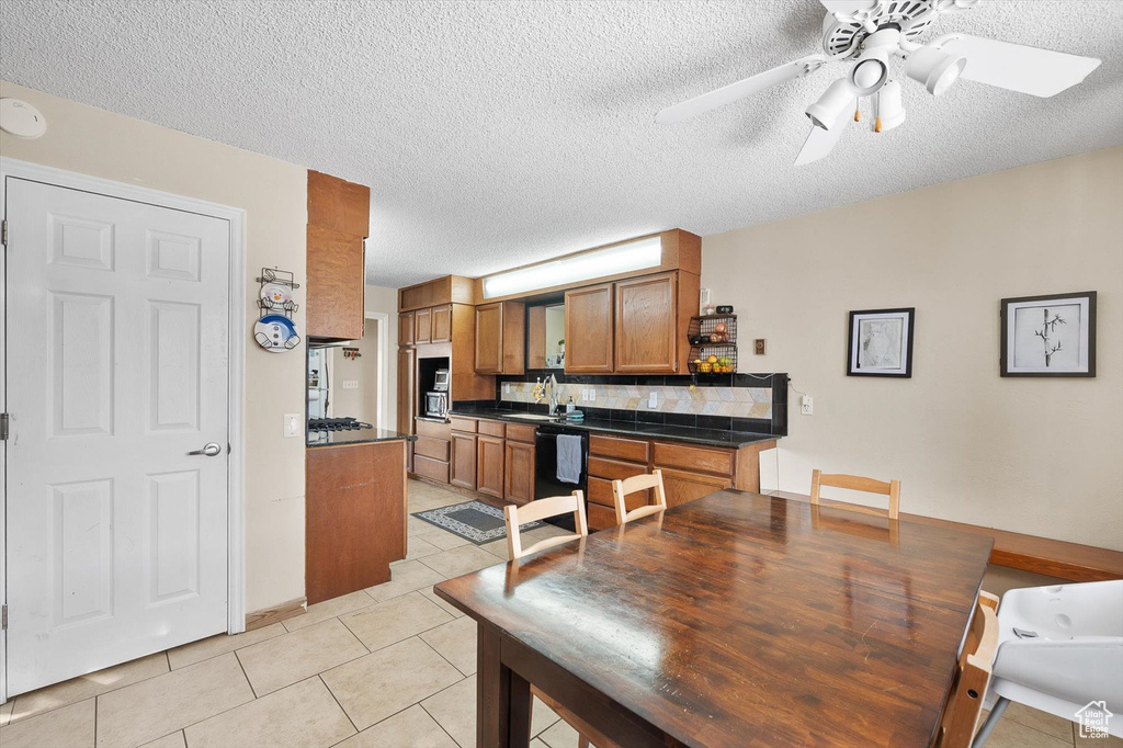Dining area with a textured ceiling, light tile floors, sink, and ceiling fan