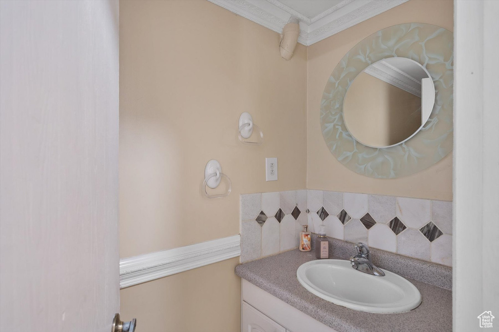 Bathroom with tasteful backsplash, ornamental molding, and vanity with extensive cabinet space