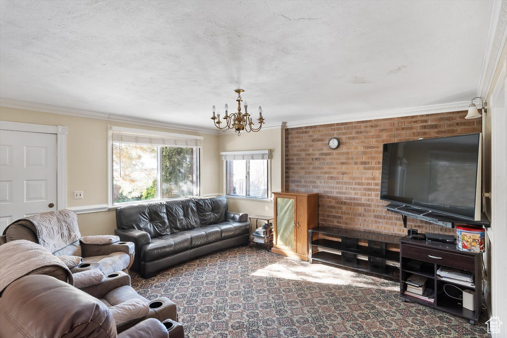Carpeted living room with an inviting chandelier, ornamental molding, brick wall, and a textured ceiling